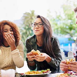 Group of friends smiling while eating outside