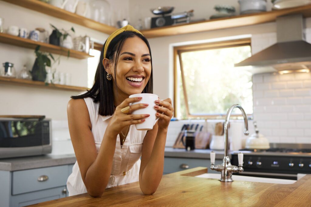 Woman smiling while drinking coffee in kitchen